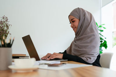 Young woman using mobile phone while sitting on table