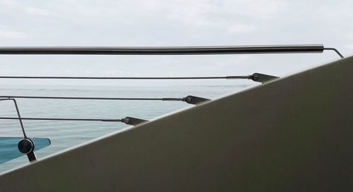 Close-up of railing by sea against sky