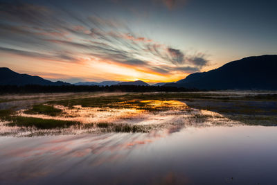 Spectacular sunrise over marshlands with mountain range in background