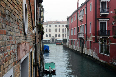 Canal amidst residential buildings against sky