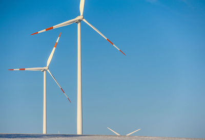 Low angle view of windmill on landscape against blue sky