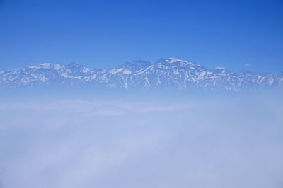 Low angle view of snow mountains against clear blue sky