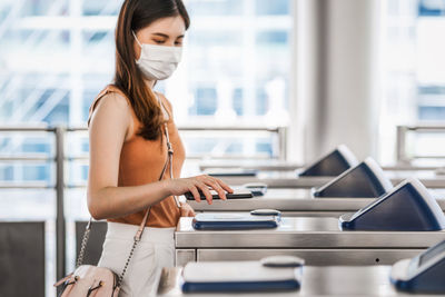 Closeup hand using smart mobile phone of young asian woman passenger wearing surgical mask 