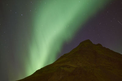 Low angle view of green mountain against sky at night