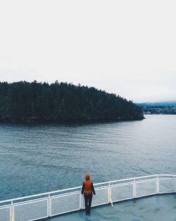 Rear view of woman standing by railing against clear sky