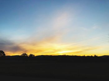 Scenic view of silhouette field against sky during sunset