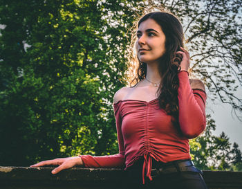 Portrait of young woman against trees