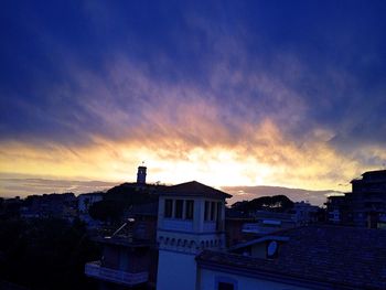 Houses in city against sky at sunset