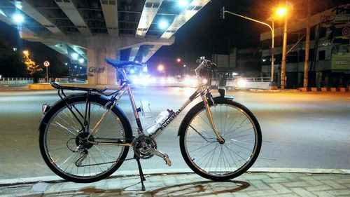Bicycle parked on footpath at night