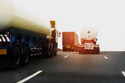 Vehicles on road against sky in city