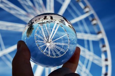 Close-up of hand holding glass against blue sky