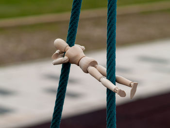 Close-up of wooden figurine hanging on ropes at playground