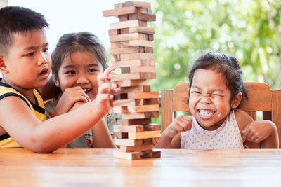 Sisters playing with wooden toy blocks on table while sitting in porch