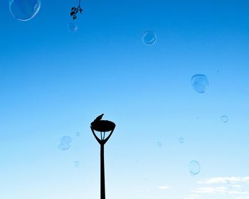 Low angle view of bubbles against blue sky