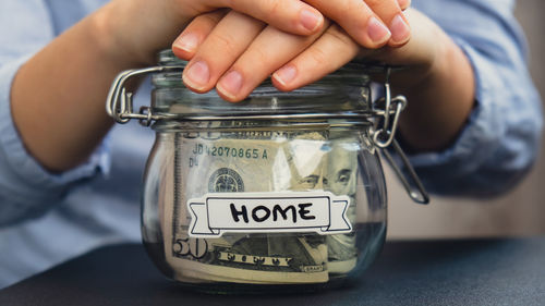 Cropped hand of person holding coin in jar