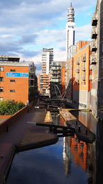 Canal amidst buildings against sky in city