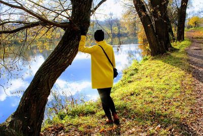 Rear view of woman standing by lake during sunny day