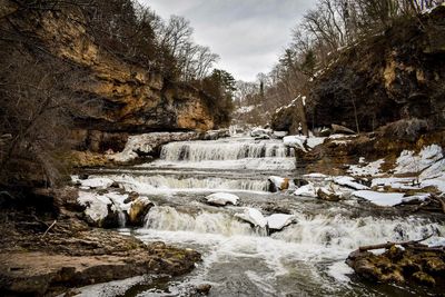River flowing through rocks against sky