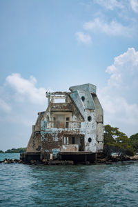 Abandoned building by sea against sky