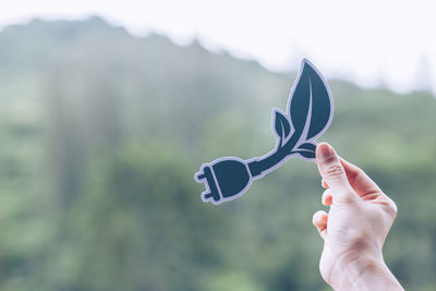 Close-up of hand holding leaf against blurred background