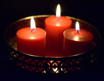 Close-up of illuminated tea light candles in darkroom