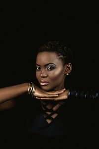 Close-up portrait of young woman against black background