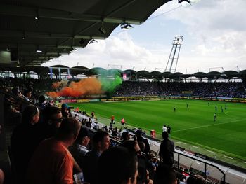 Group of people looking at stadium against sky