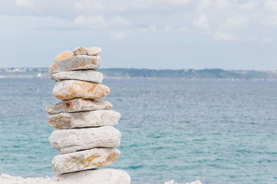 Stack of stones in sea against sky