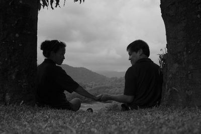 Rear view of couple holding hands against sky