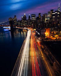 High angle view of light trails on road amidst buildings at night