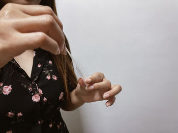 Midsection of woman holding hands against white background