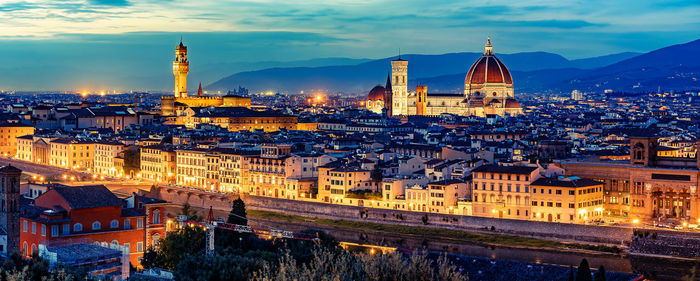 Illuminated buildings in city against sky