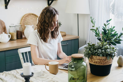 Beautiful woman in the kitchen working on a laptop.