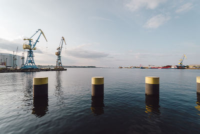 Cranes at harbor against sky