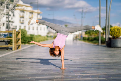 Young woman exercising handstand at footpath