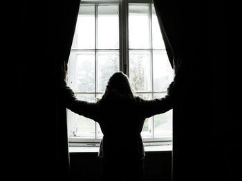 Young woman looking through window
