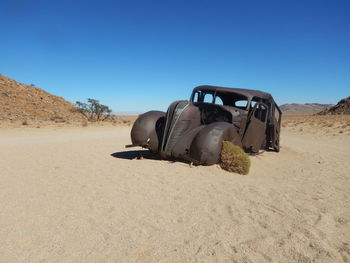 Horse cart on sand dune against clear sky