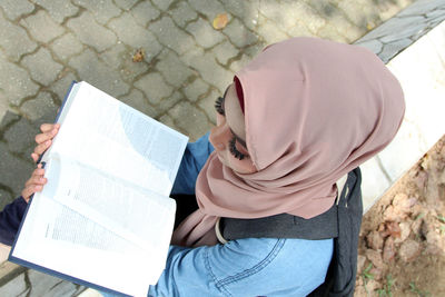 High angle view of woman reading book outdoors