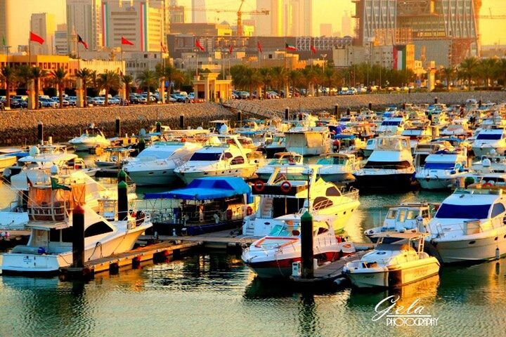 nautical vessel, moored, in a row, large group of objects, water, building exterior, boat, abundance, architecture, transportation, arrangement, built structure, side by side, mode of transport, table, city, reflection, waterfront, restaurant, chair