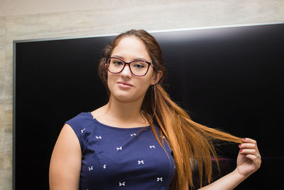 Portrait of young woman against television set at home