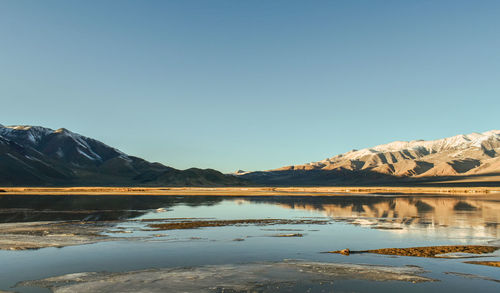 Scenic view of lake and mountains against clear blue sky