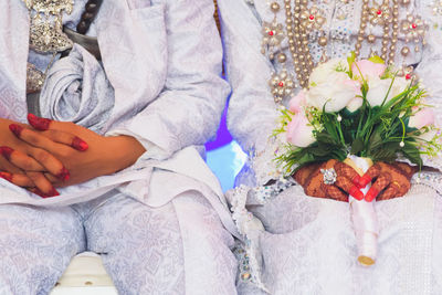 Midsection of bride and bridegroom wearing traditional clothing during wedding ceremony