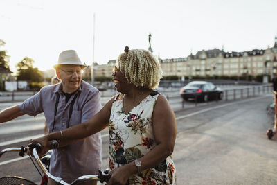 Cheerful couple with bicycle on road in city