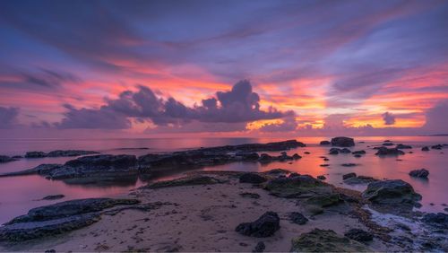 Scenic view of rock formation at sea against sky during sunset