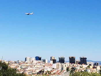 Airplane over town against clear blue sky