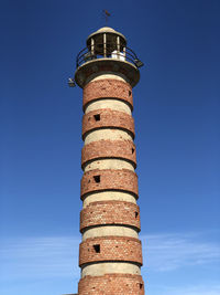 Low angle view of old brick built lighthouse tower against blue sky