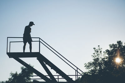 Low angle view of man working on steps against clear sky