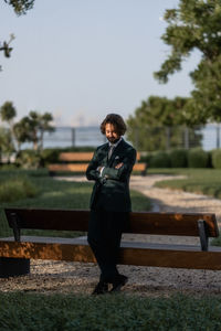 Side view of man sitting on bench in park