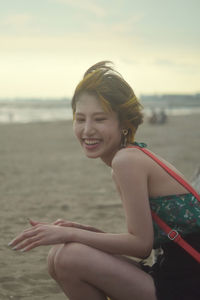 Portrait of a smiling young woman sitting on beach