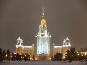 Illuminated buildings against clear sky at night